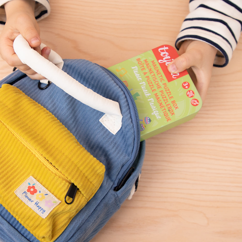 Nahaufnahme, wie ein Kind eine Toydea Magnetspiel-Box in einen Rucksack packt, ideal für Reisen und unterwegs.